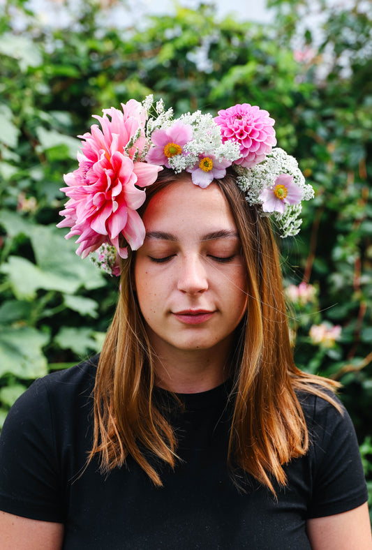 Jeune fille portant une couronne réalisée avec des fleurs fraiches de couleur rose et blanche. Les fleurs sont belles et volumineuses