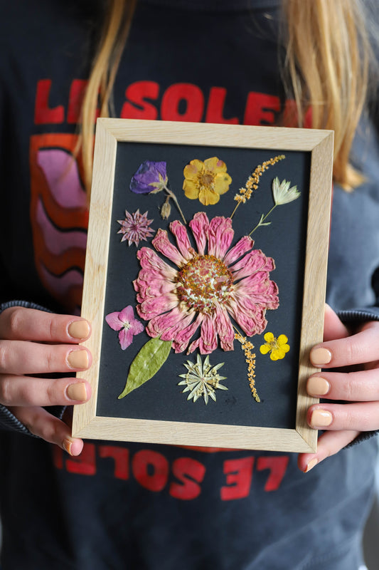 cadre en bois avec des fleurs pressées colorées sur fond noir