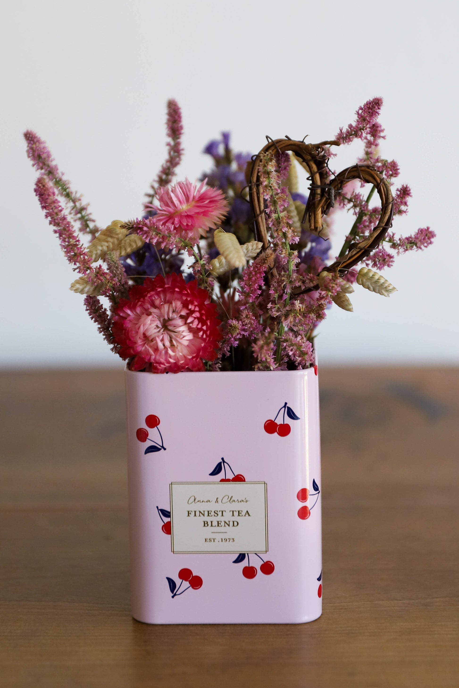 composition de fleurs séchées dans les tons roses présentée dans une boite à thé en métal