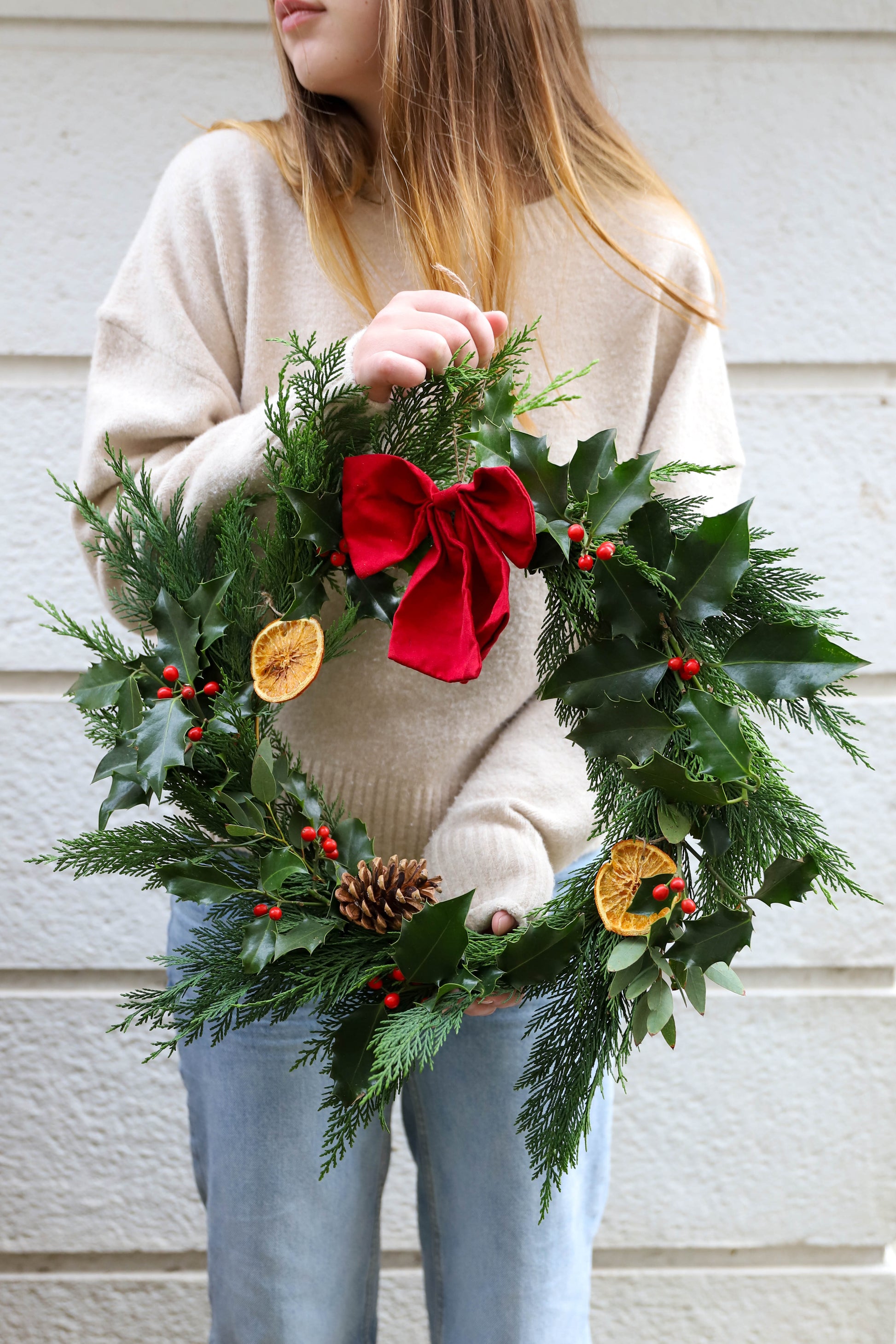 couronne de Noël française traditionnelle avec des fleurs et des branches fraiches aux couleurs traditionnelles vert et rouge