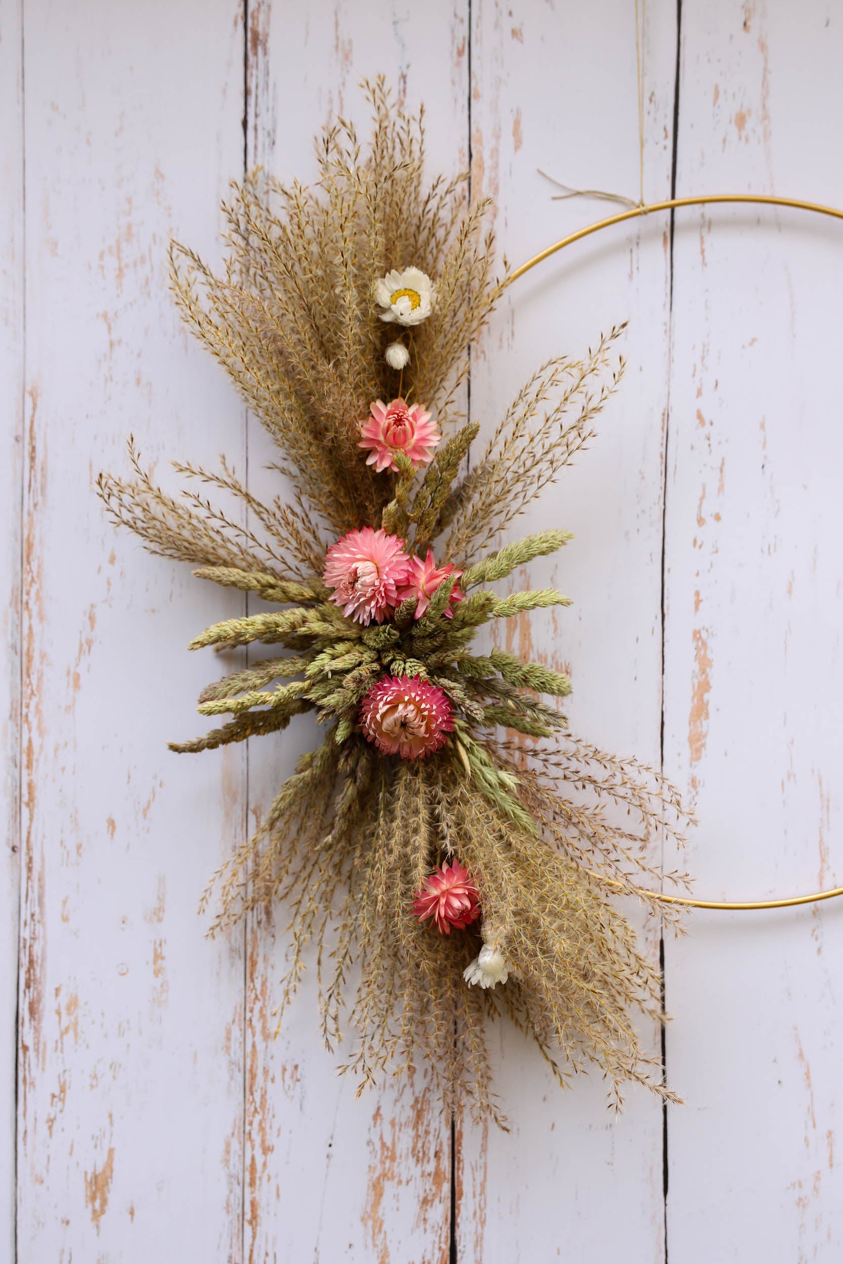 couronne de fleurs séchées rose pâle et des graminés sur un cercle de métal