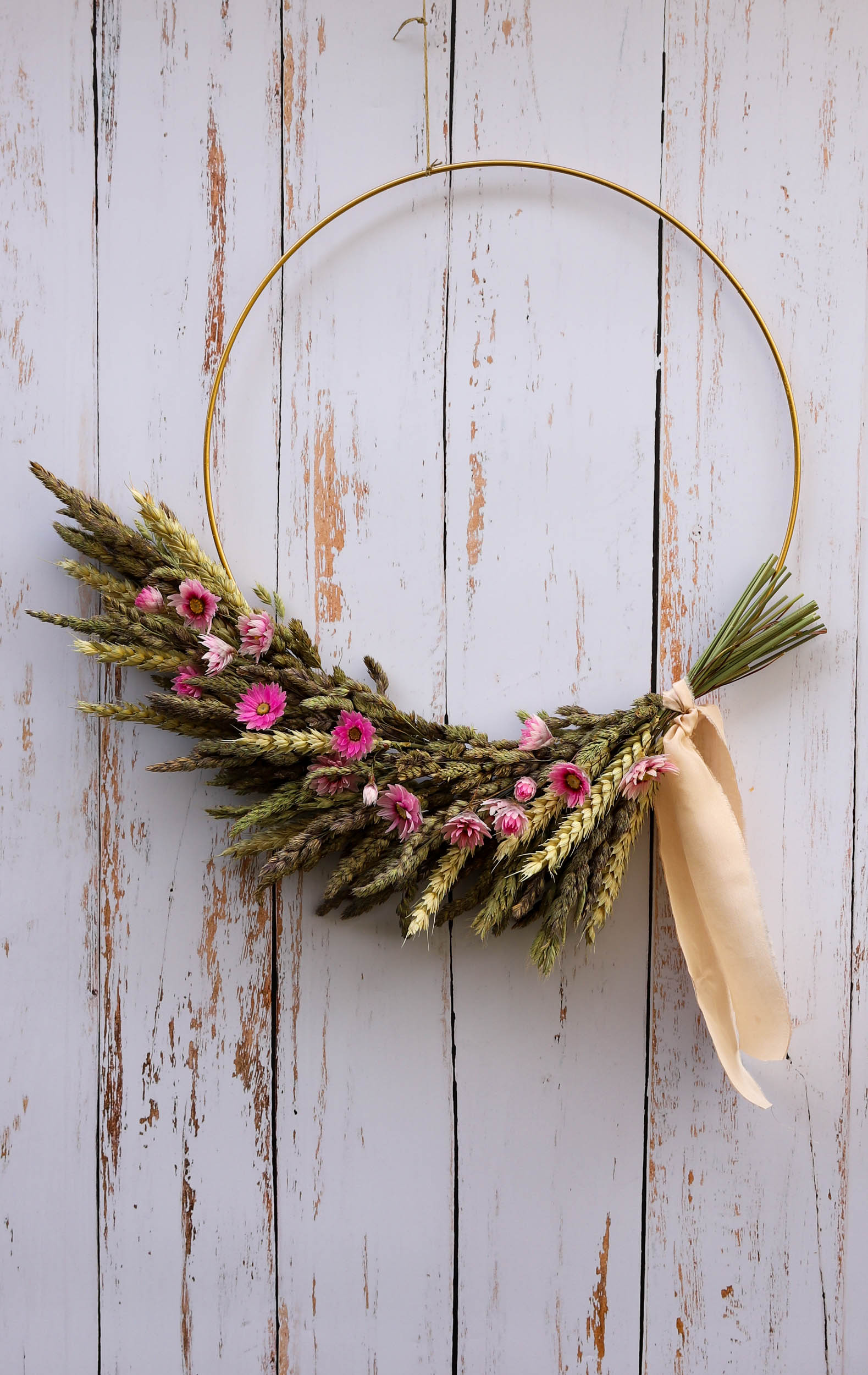 couronne de fleurs séchées roses avec du blé et des graminés. Les fleurs sont fixées sur un cercle de métal