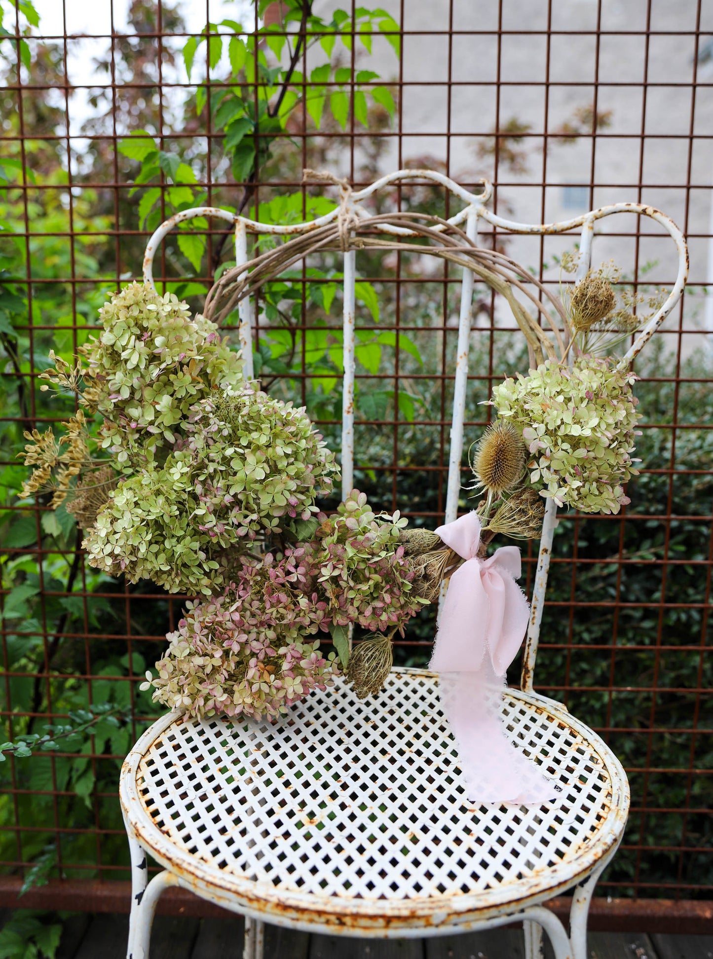 couronne d'hortensias séchés avec un gros ruban posé sur une chaise vintage