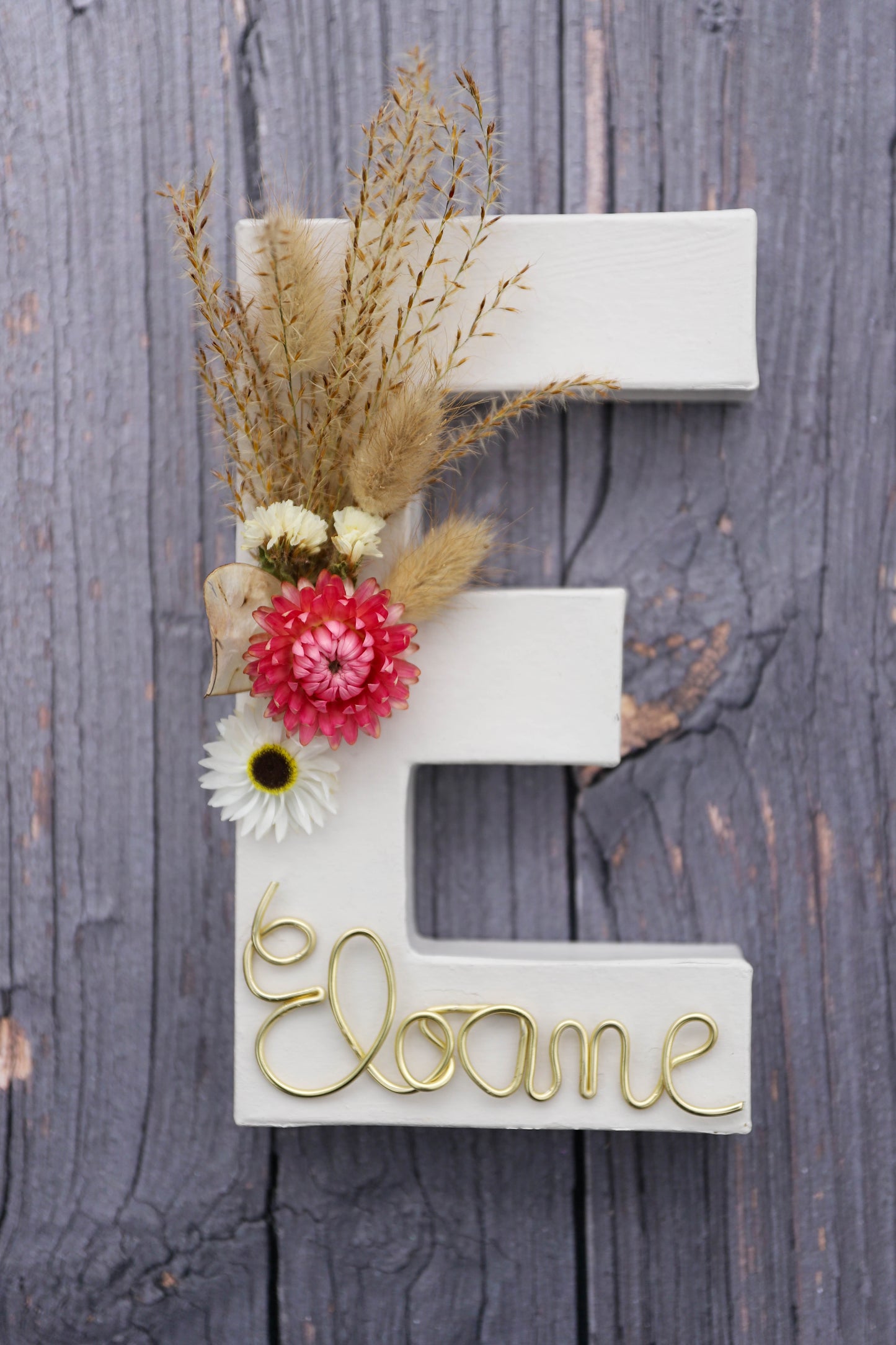 Lettre en carton décorée avec des fleurs séchées naturelles et le prénom écrit avec un fil de fer
