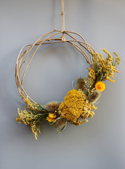 couronne de sarments de glycine avec des fleurs séchées jaunes et des chardons séchés