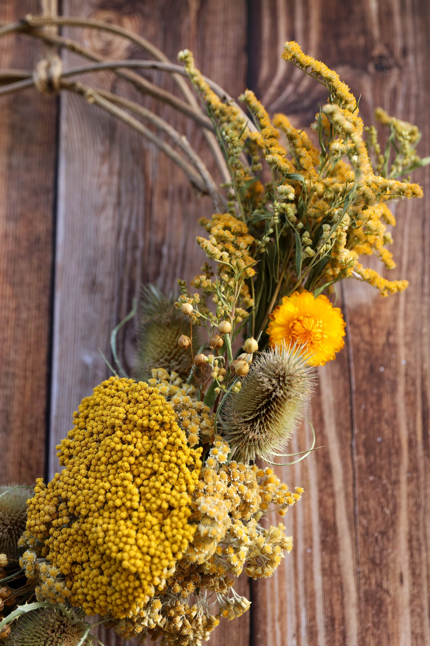 couronne de fleurs séchées avec des achillées jaunes, des immortelles et des chardons